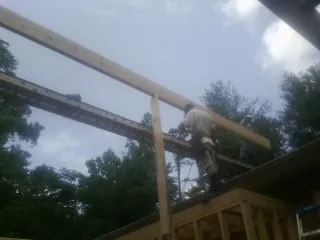 Carpenter setting a ridge beam over a new addition frame — Ice Dam Removal by Roofing Brothers in Ricketts