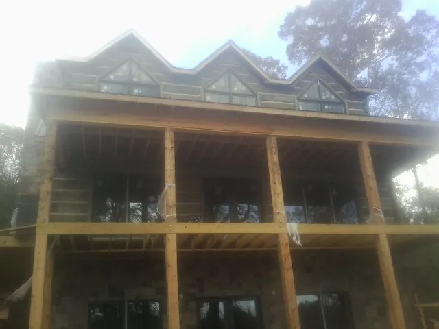 Dormers and porch framing on a large log home under construction — Roof Coating work by our crew in Ricketts
