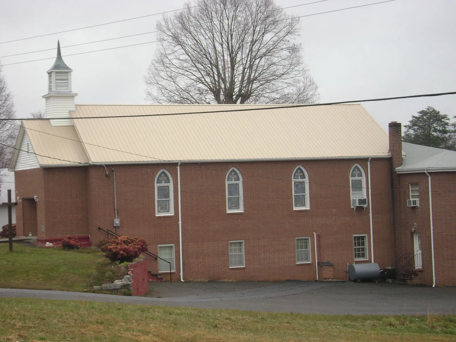 New tan metal roof on a brick church with a white steeple in Ricketts