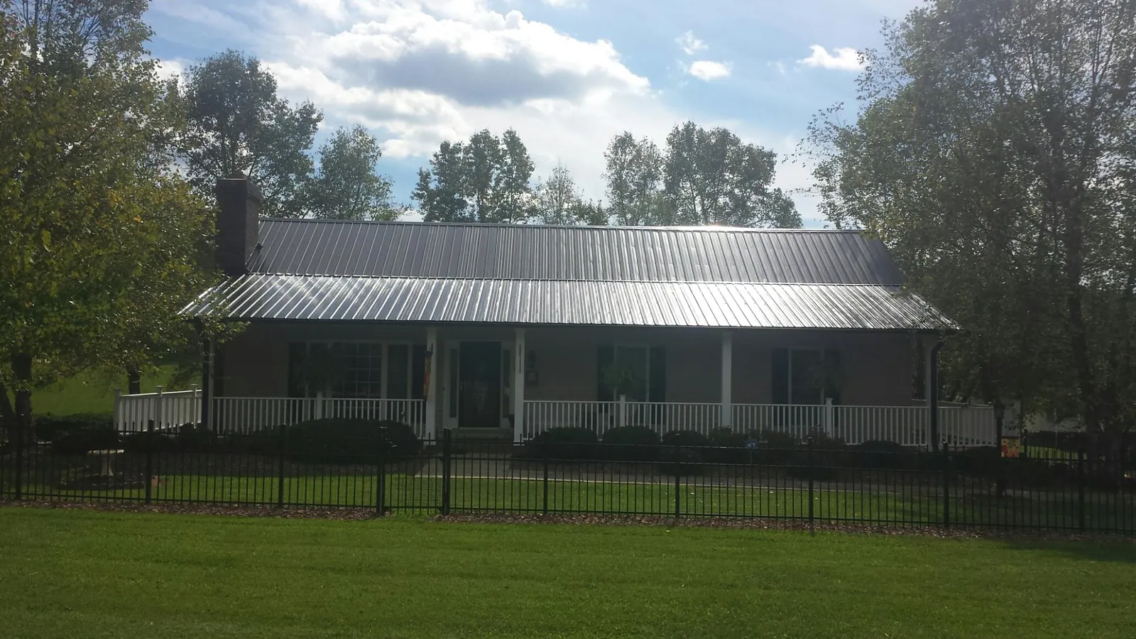 Gray metal roof on a brick ranch with a full width front porch — Gutter Guard Installation work by our crew in Ricketts
