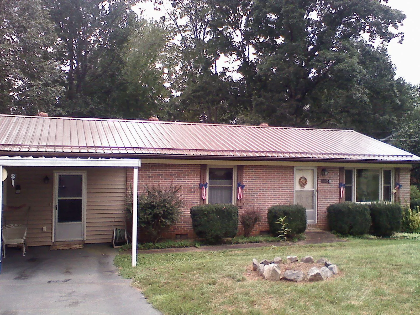 Bronze metal roof and carport on a brick ranch home — Roof Repair work by our crew in Ricketts