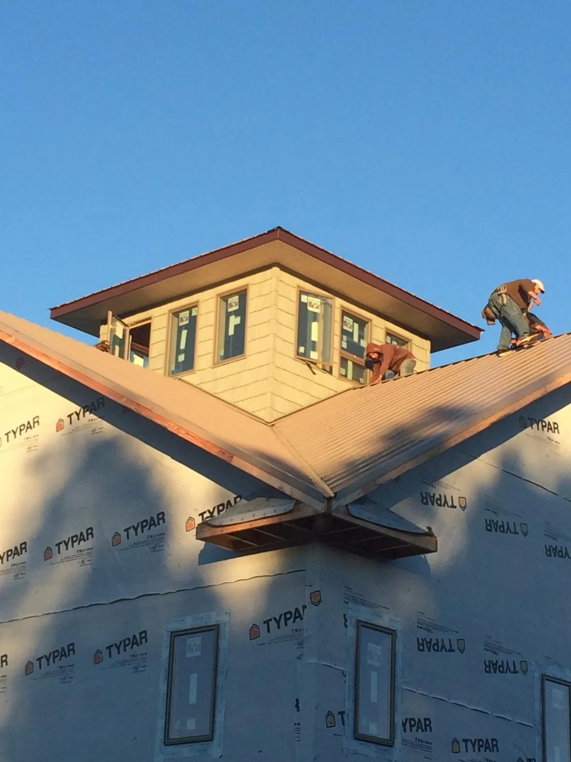 Roofers working around a rooftop cupola on a new metal roof at sunset — Roof Waterproofing in Ricketts by Roofing Brothers